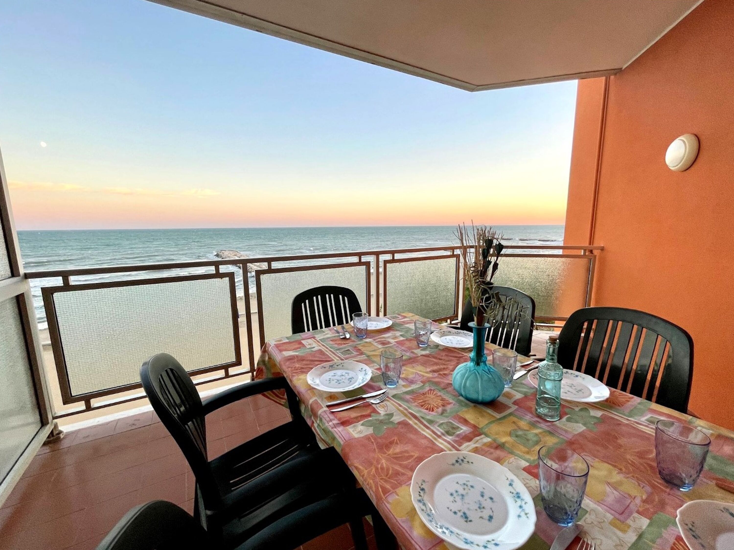 A dining table set for two with a view of the ocean.
