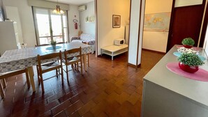 Un espacio habitable compacto con comedor, kitchenette y una pequeña zona de estar.