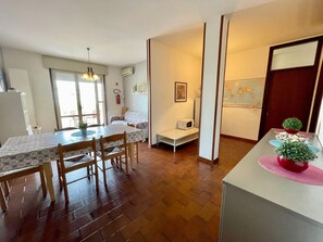 A compact living space with a dining area, kitchenette, and a small seating area. - Cozy Flat With Shared Outdoor Pool (Caorle)