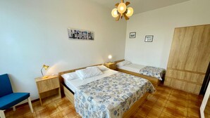 Un dormitorio con dos camas, un armario de madera, un escritorio y una silla.