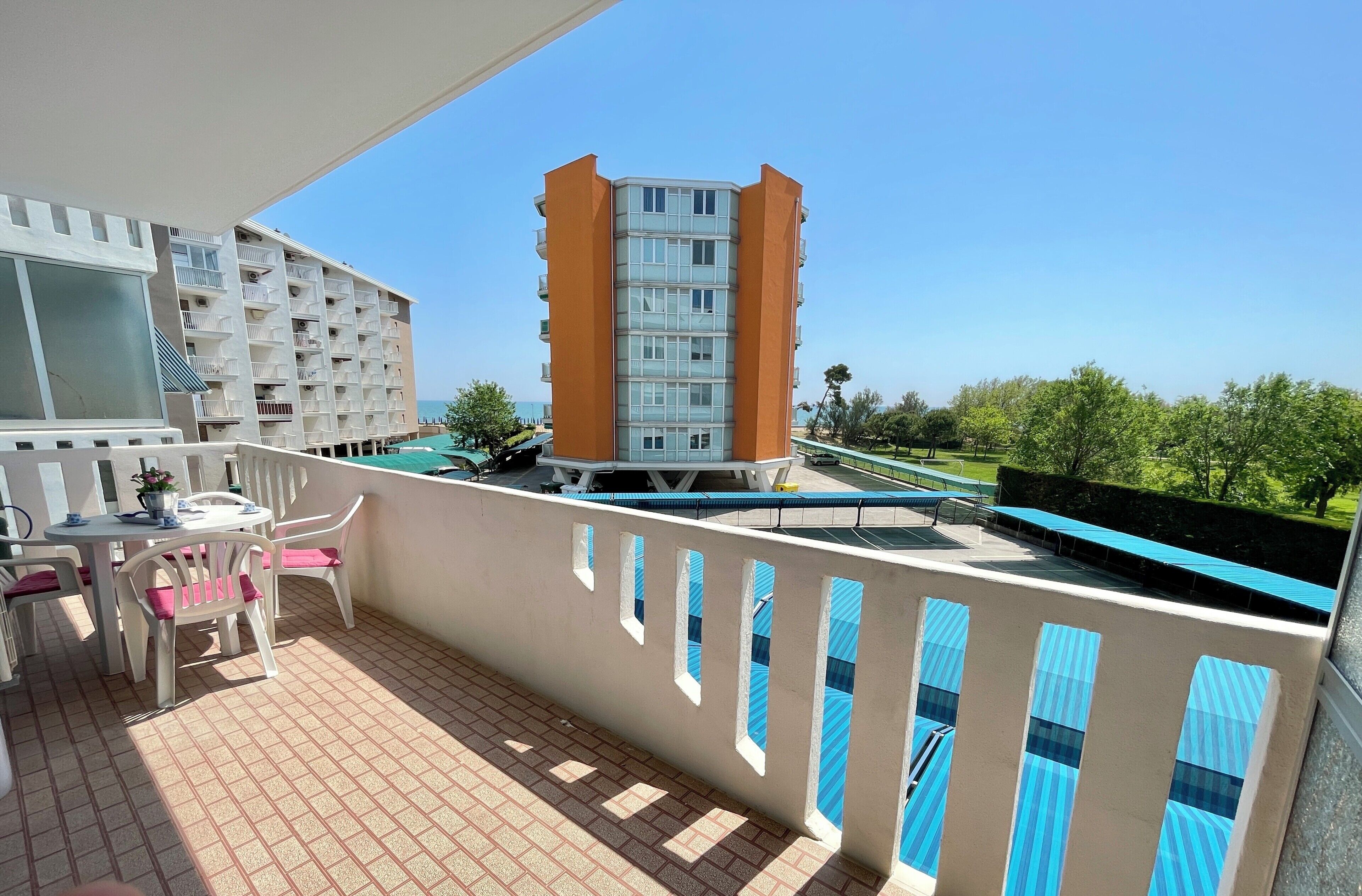 A balcony with a pool, a table with chairs, and a view of a high-rise building.