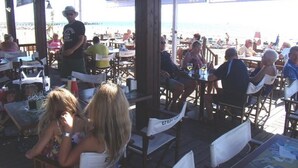 Un ristorante sulla spiaggia con posti a sedere all'aperto, tavoli e ombrelloni.