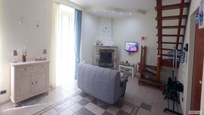 Ein Wohnzimmer mit Kamin, Fernseher, Sofa und einer Leiter.