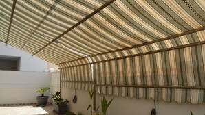 A covered outdoor area with a checkered floor, potted plants, and a striped awning. - Gallipoli Apartment - Activelife (Gallipoli)