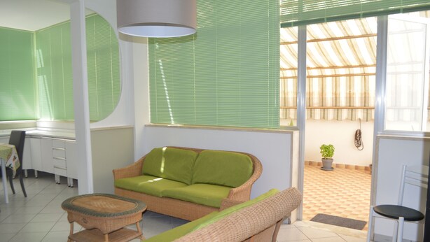 A room with a green sofa, wicker chairs, a small table, and a desk. - Gallipoli Apartment - Activelife (Gallipoli)