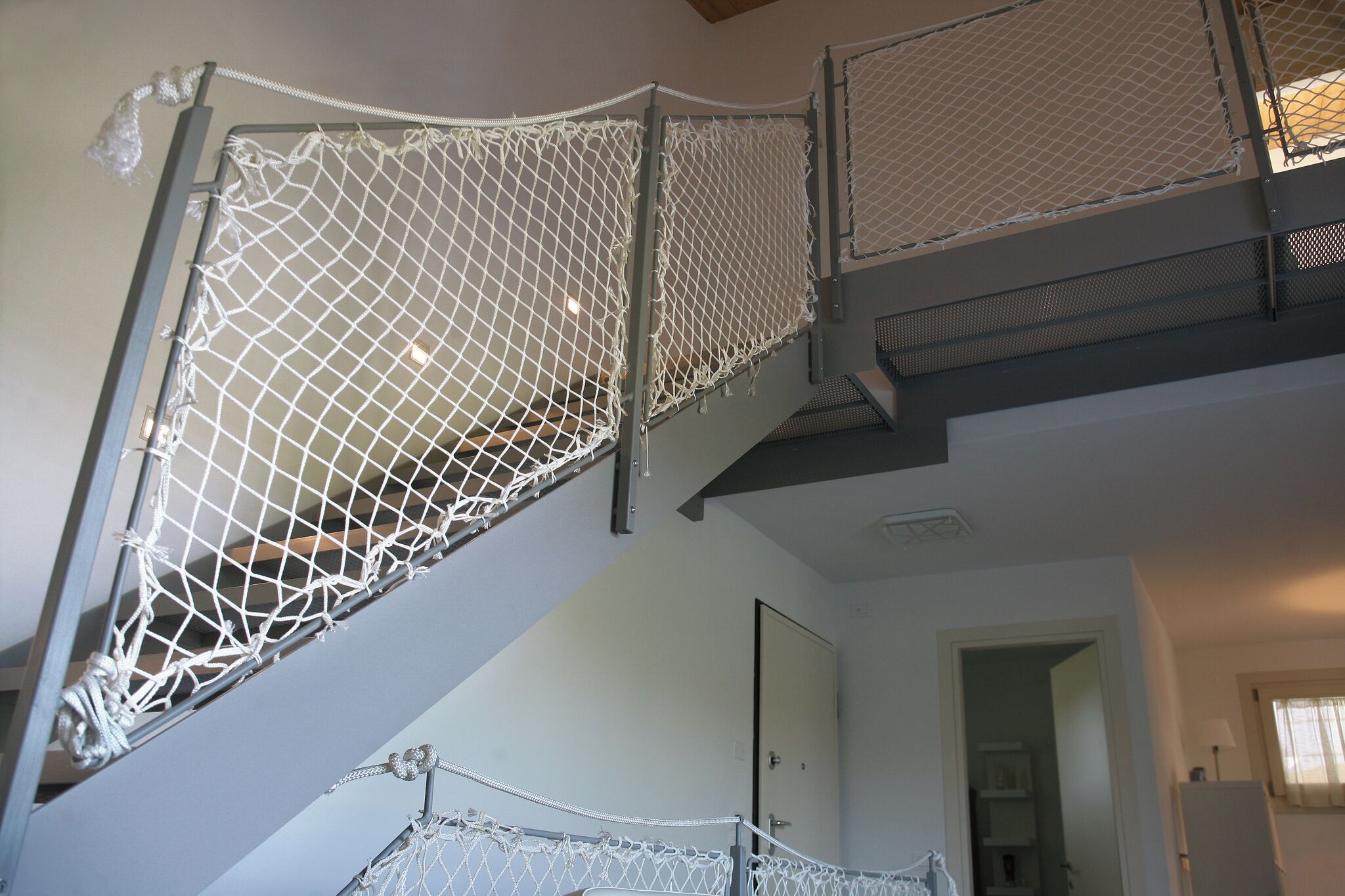 A staircase with a netted handrail and metal railings.
