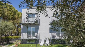 Un edificio moderno de dos pisos con balcones, un jardín y cielo despejado.