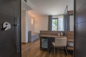 Camera d'albergo compatta con angolo cottura, un piccolo frigorifero, zona salotto e doccia.