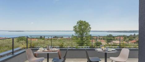 A terrace with a table and chairs, overlooking a body of water and a distant landscape.