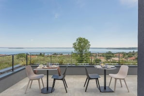 Une terrasse avec une table et des chaises, donnant sur une étendue d’eau et un paysage lointain.