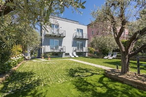Un bâtiment moderne doté de balcons, d’une pelouse bien entretenue et d’un espace extérieur aménagé pour s’asseoir.