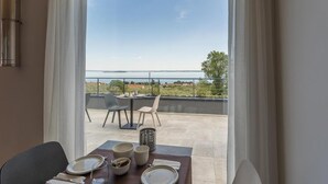 Comedor con vistas al mar y balcón con mobiliario exterior.