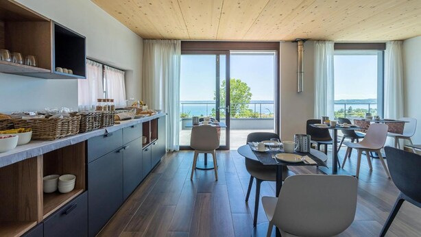 Una cocina moderna con techo de madera, un comedor con vista al mar y un balcón con mesa y sillas.
