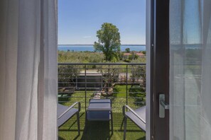 A balcony with a view of the sea, a tree, and a grassy area with a table and chairs. - Room-insula Felix - Deluxe Double Room w (Moniga del Garda)