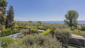 Una piscina envoltada de vegetació exuberant amb una vista despejada del mar.