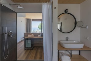 Une salle de bain moderne avec un grand miroir, un lavabo et une douche.