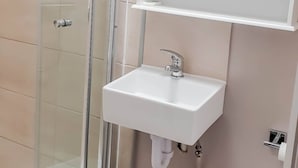 A bathroom with a glass shower enclosure, a white sink with a chrome faucet, and a mirrored medicine cabinet above it. - Room-cosy Double Private Bedroom 2-3 (Dudley)