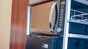 A compact, modern kitchen with a built-in microwave and oven, a small refrigerator, and a bar cooler. - Room-cosy Double Private Bedroom 2-3 (Dudley)