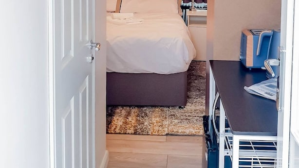A hotel room with a bed, a nightstand, a desk, and a chair. - Room-cosy Double Private Bedroom 2-3 (Dudley)
