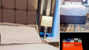 A hotel room with a tufted headboard, a bedside lamp, a neatly made bed with white linens, and a folded towel on the bed. - Room-cosy Double Private Bedroom 2-3 (Dudley)