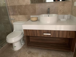 A bathroom with a toilet, a sink with a mirror, and a wooden vanity. - Luxurious Charming Studio-terrace With Pool-gym (Playa del Carmen)