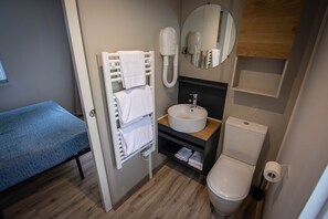 Une petite salle de bain d’hôtel comprenant un lavabo, des toilettes et un porte-serviettes avec plusieurs serviettes.
