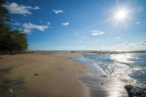Una playa con cielo despejado, mar tranquilo y horizonte lejano.