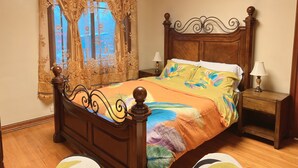 A bedroom with a wooden bed, floral curtains, and a view of the street through the window. - Beautiful Well Preserved Historical 2 bedroom House. 1112B (Glenwood Springs)