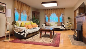 A living room with two sofas, a coffee table, a TV, and a fireplace. - Beautiful Well Preserved Historical 2 bedroom House. 1112B (Glenwood Springs)