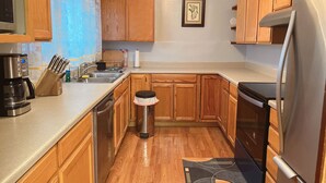 A kitchen with wooden cabinets, a stainless steel refrigerator, a coffee maker, and a dish rack. - Beautiful Well Preserved Historical 2 bedroom House. 1112B (Glenwood Springs)