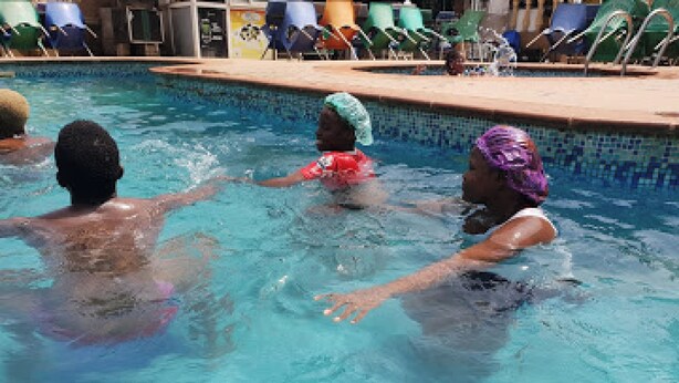 A swimming pool with people in it. - Room-sheriffyt Royale Hotel - Guest Suit (Ikorodu)