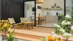 A modern outdoor patio with wooden furniture, a small table, and potted plants.