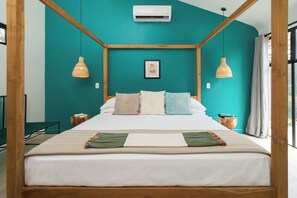 Un lit à baldaquin avec un mur de couleur turquoise et des poutres en bois, un tableau encadré au-dessus du lit, et deux tables de chevet avec des lampes.