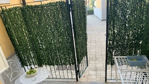 A patio area with a white metal table and chairs, a small round table with a bowl of fruit, and a metal bench. - All the Comforts of a Hotel With the Spaces of a Home (Castellammare di Stabia)