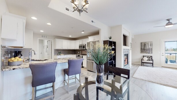 A modern kitchen with white cabinets, a central island with bar stools, a built-in microwave, and a stainless steel refrigerator. - Lavish Tranquil No-Steps Oasis (Westminster)