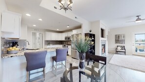 A modern kitchen with white cabinets, a central island with bar stools, a built-in microwave, and a stainless steel refrigerator. - Lavish Tranquil No-Steps Oasis (Westminster)