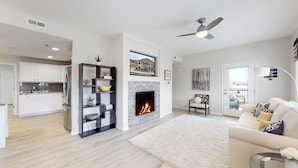 A modern living room with a fireplace, a sofa, a coffee table, and a dining area with a kitchen visible in the background. - Lavish Tranquil No-Steps Oasis (Westminster)