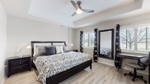 A bedroom with a bed, bedside tables, a desk, a chair, a ceiling fan, and a window with curtains. - Lavish Tranquil No-Steps Oasis (Westminster)