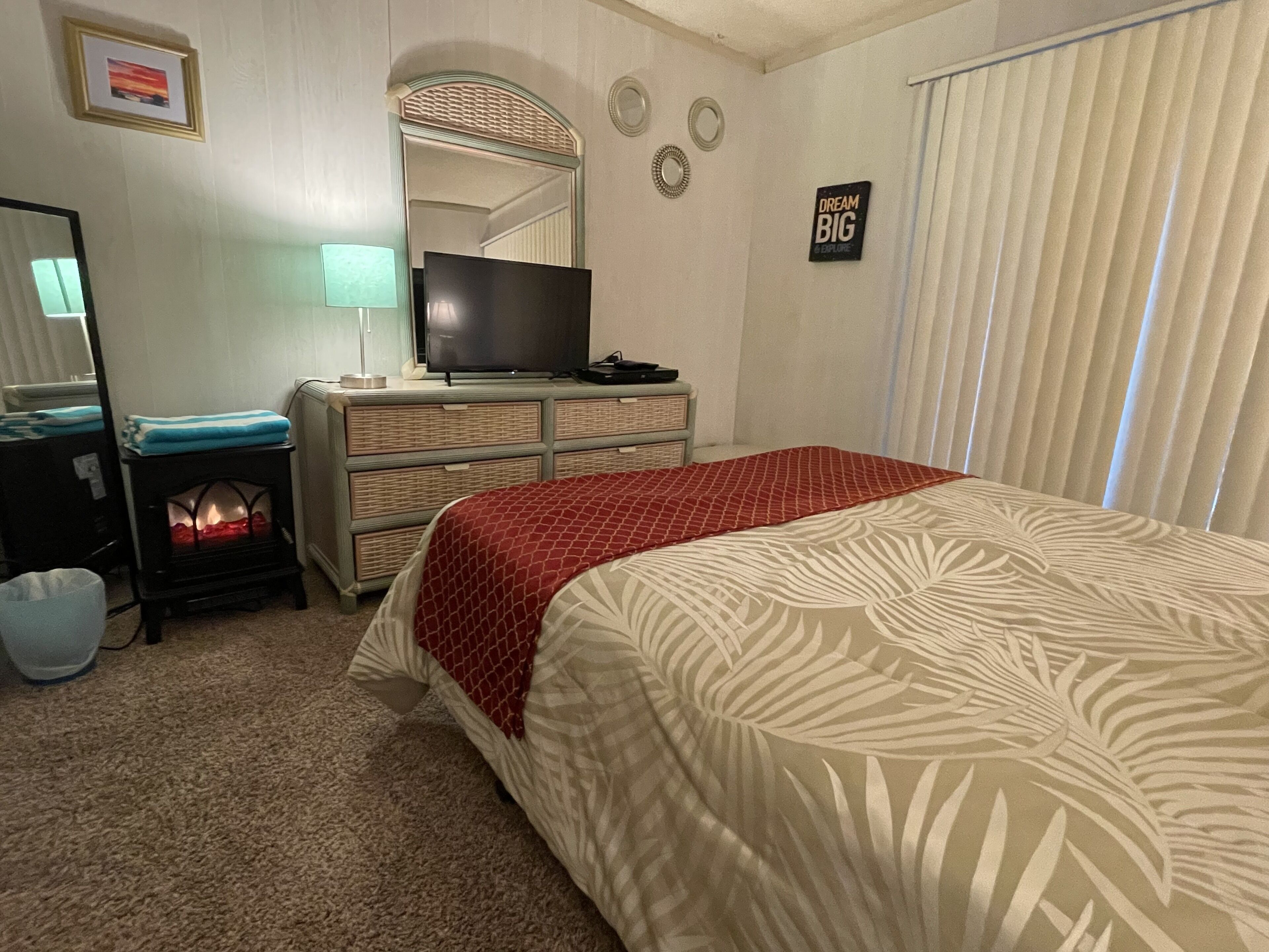 Un dormitorio con cama, cómoda, televisor y espejo.
