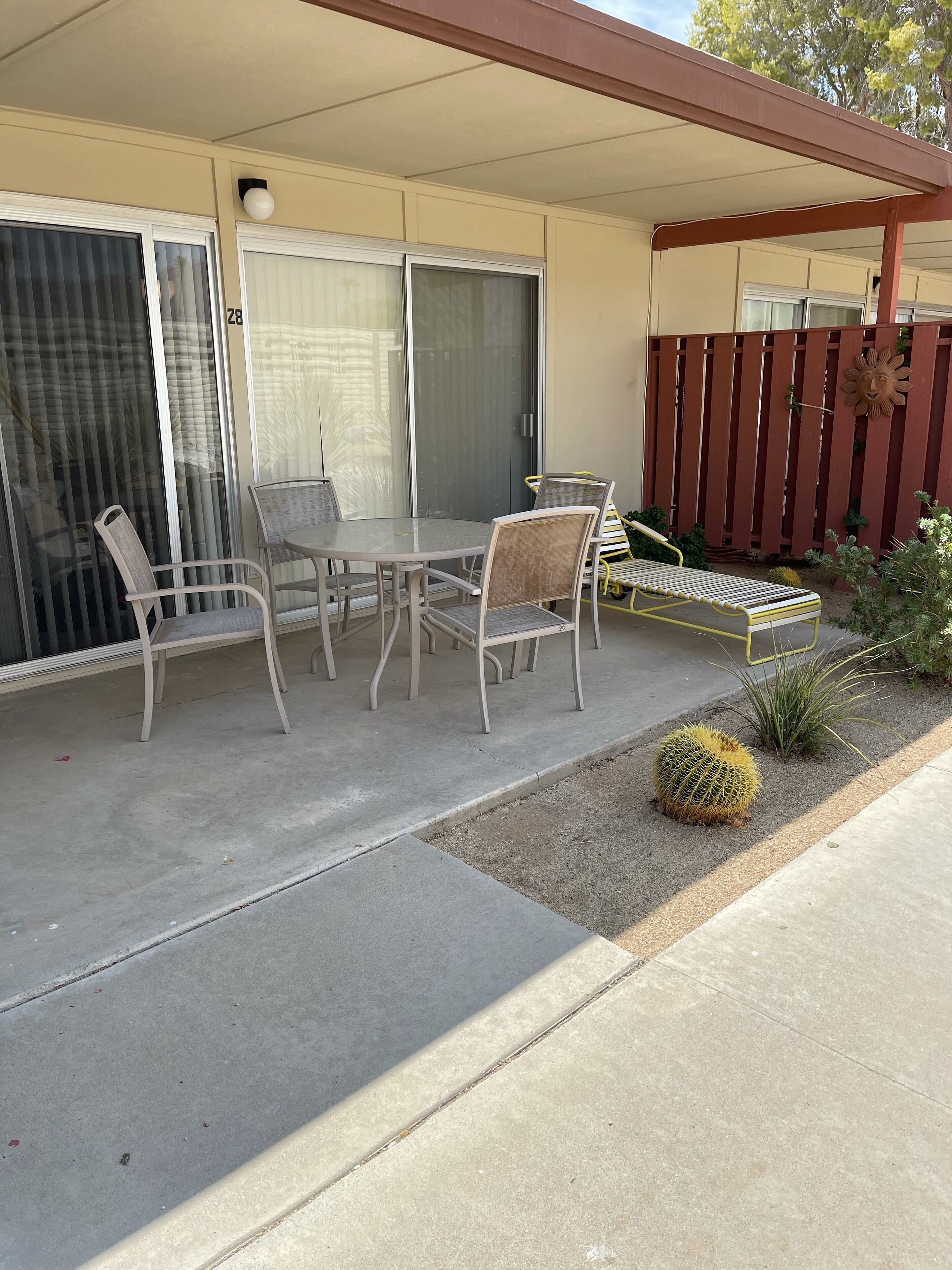 Un patio con una mesa y sillas, una puerta corrediza de vidrio y una valla de madera.