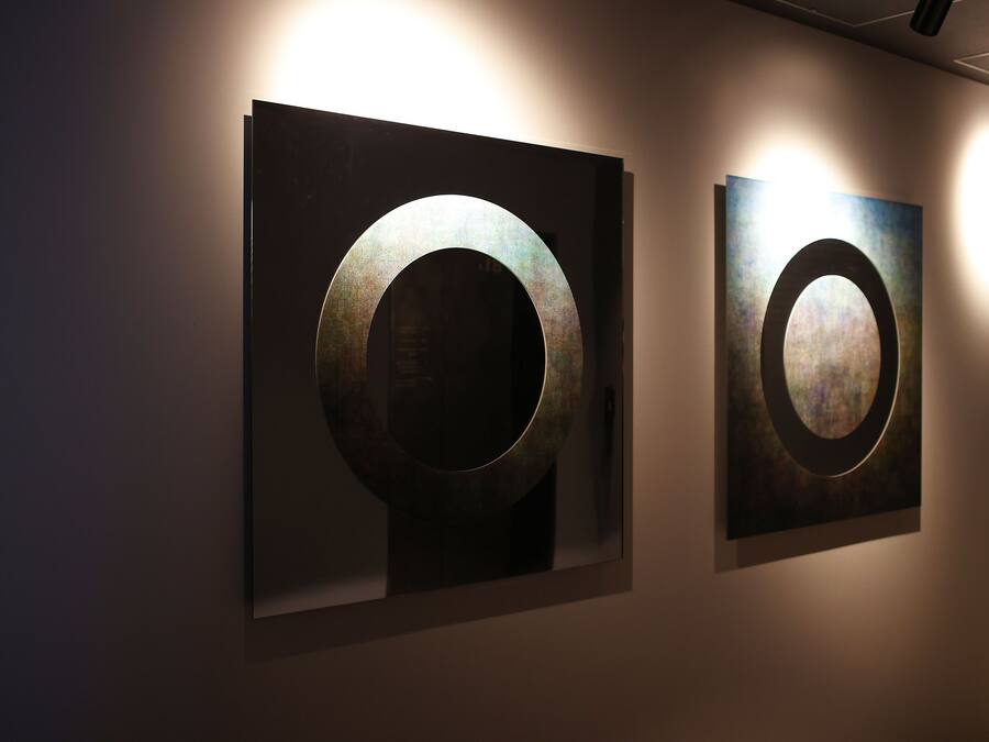 Two framed circular artworks on a wall in a hallway.