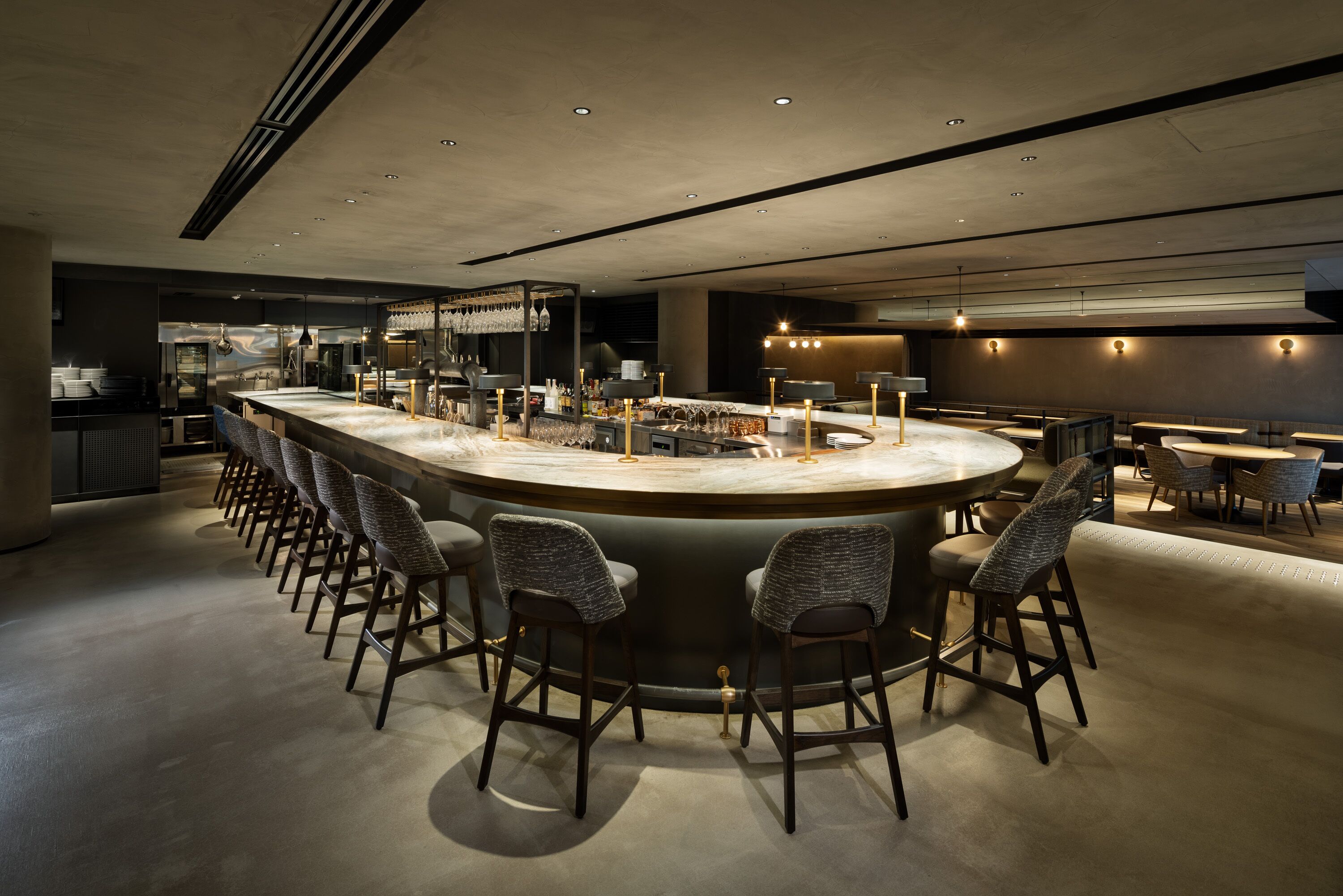 A modern bar area with a curved counter, bar stools, and ambient lighting.