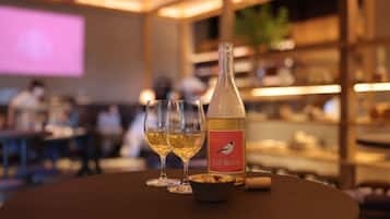 Une bouteille de vin Soif Blanc, deux verres et un bol de noix sur une table dans un restaurant.