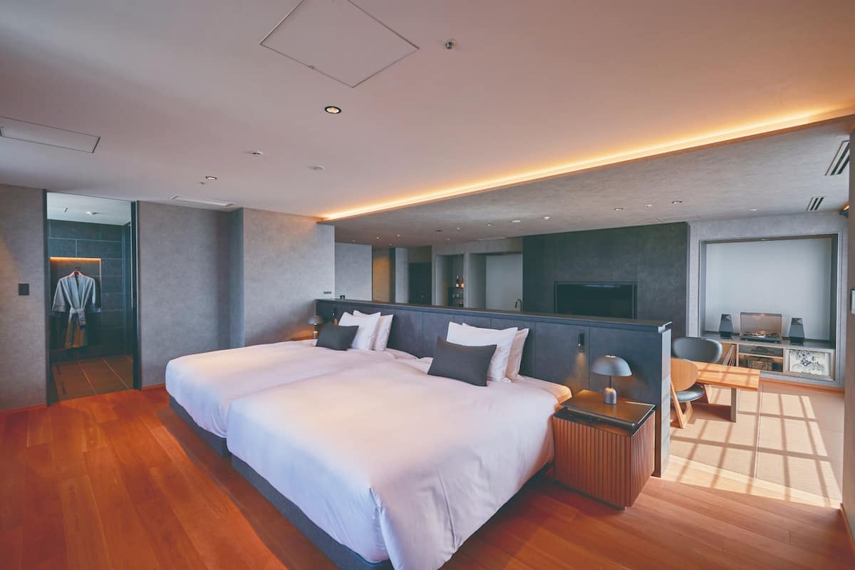 Une chambre d’hôtel moderne équipée d’un grand lit, d’un bureau avec une chaise, d’une télévision et d’un miroir.