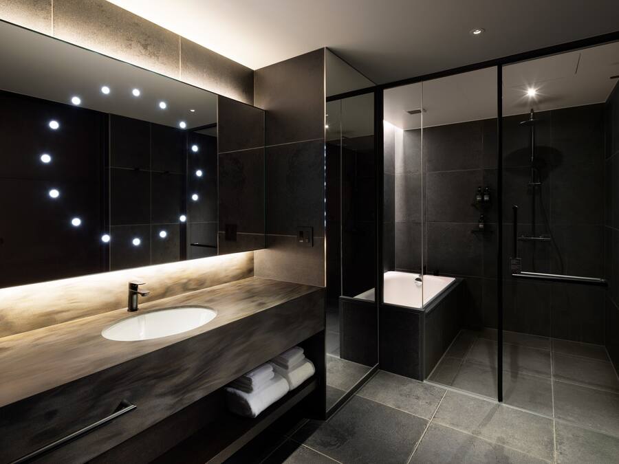 A modern bathroom with a large mirror, a sink, and a shower area.