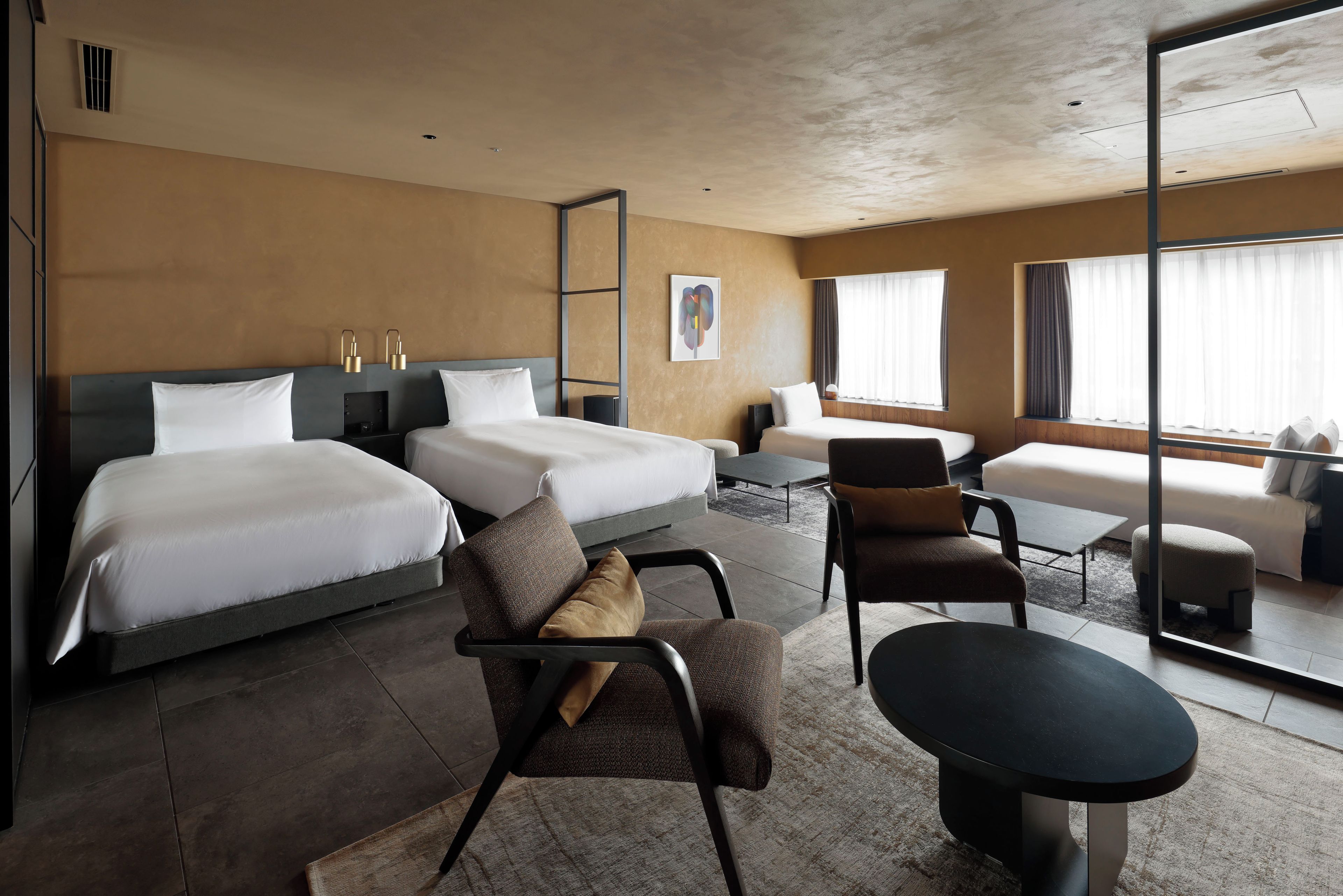 A hotel room with two beds, a sofa, a chair, a small table, and a large window.