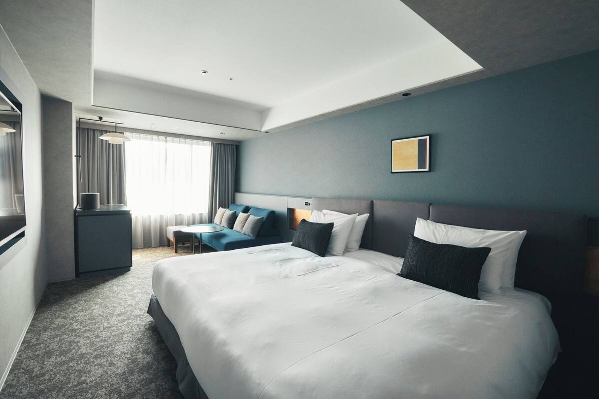 Une chambre d’hôtel moderne dotée d’un grand lit, d’un bureau et d’un coin salon.