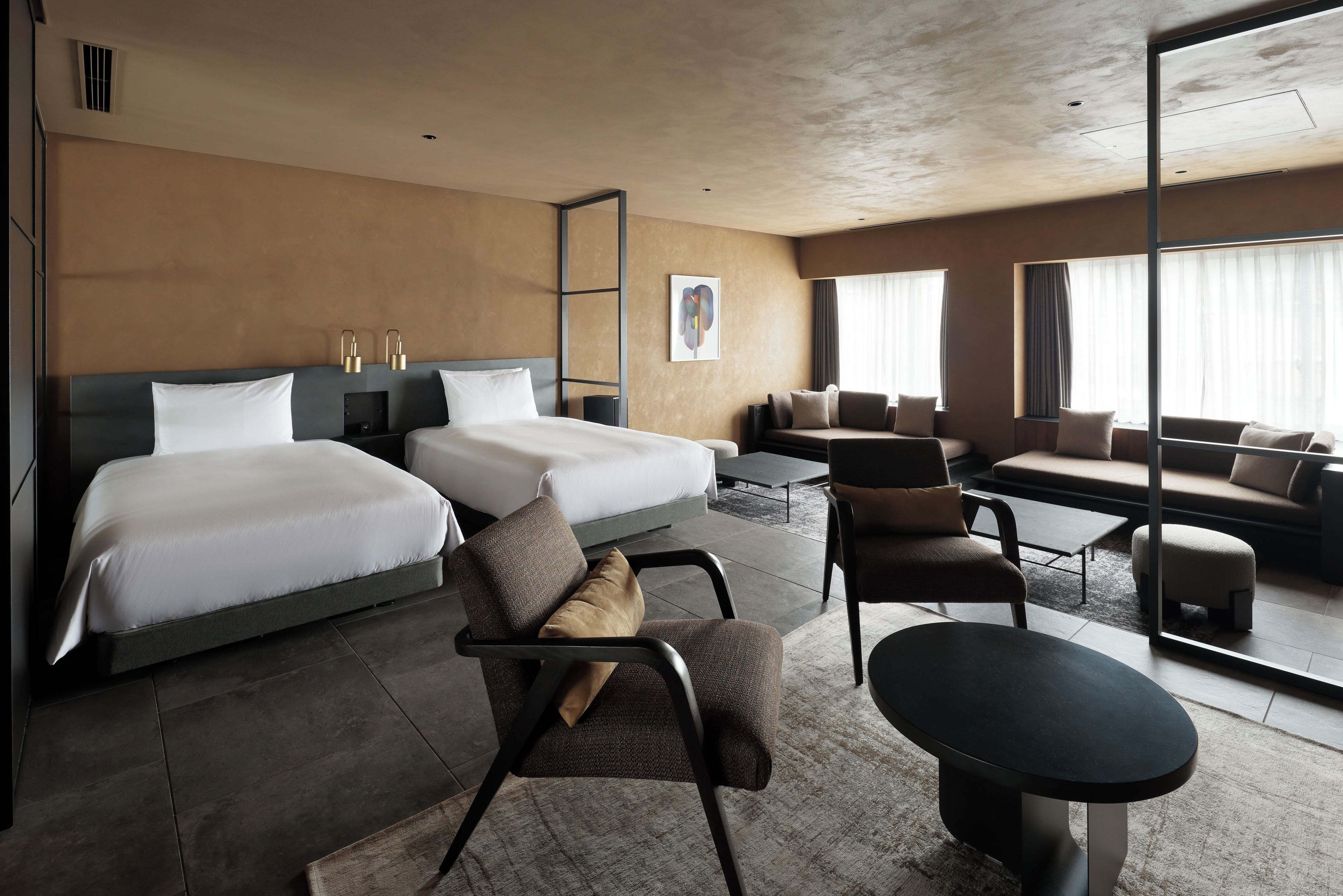 A modern hotel room with two beds, a sofa set, a dining table, and a large window.
