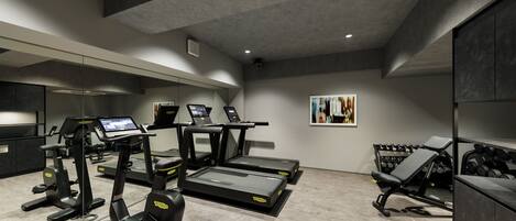 A modern gym with treadmills, a weight bench, and dumbbells.