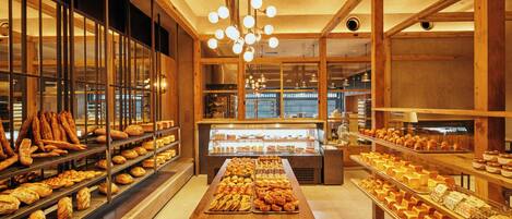 Een bakkerij met houten balken, een centrale displaytafel en schappen vol gebak.